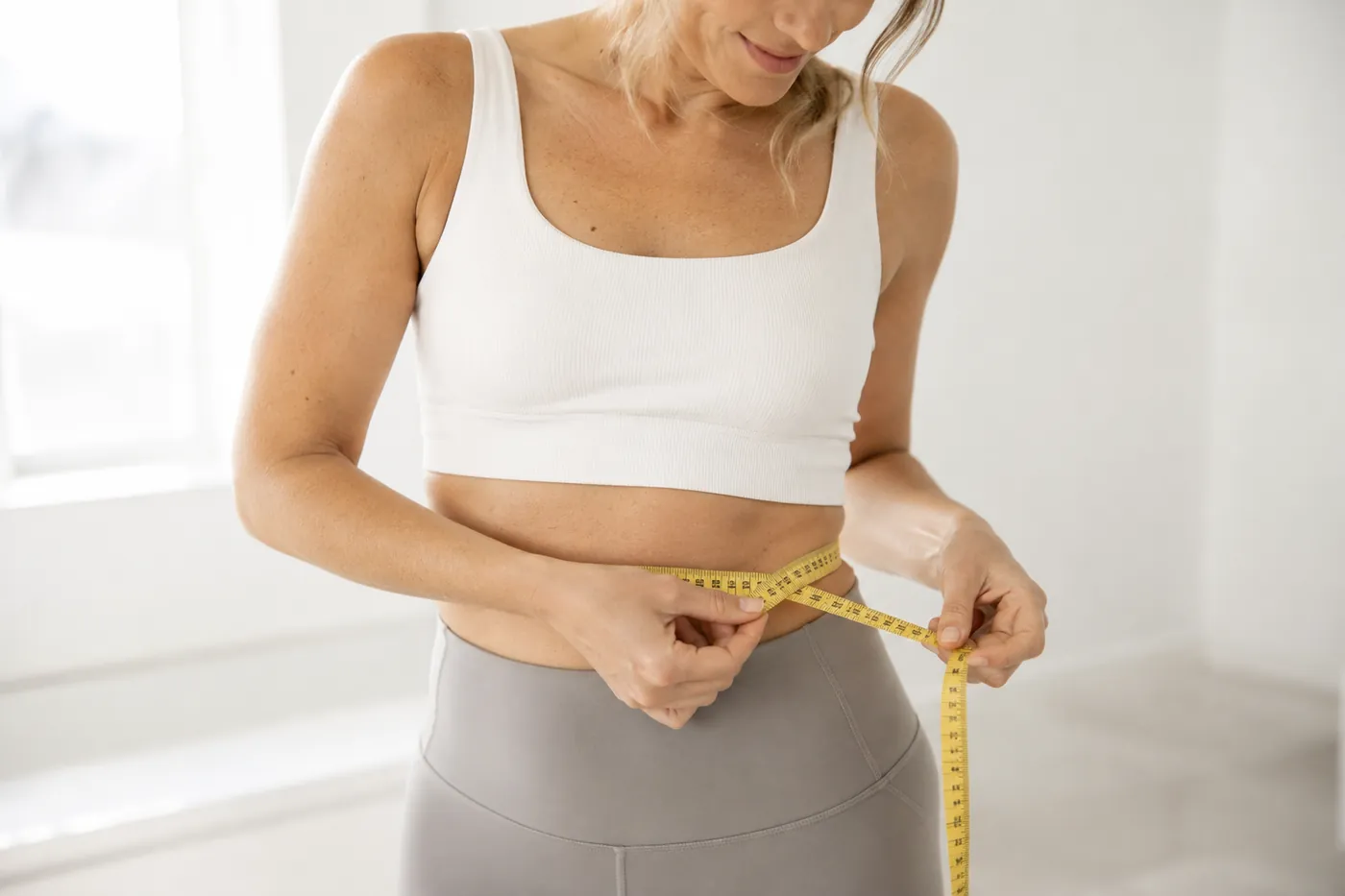 Woman measuring her waist with a tape measure